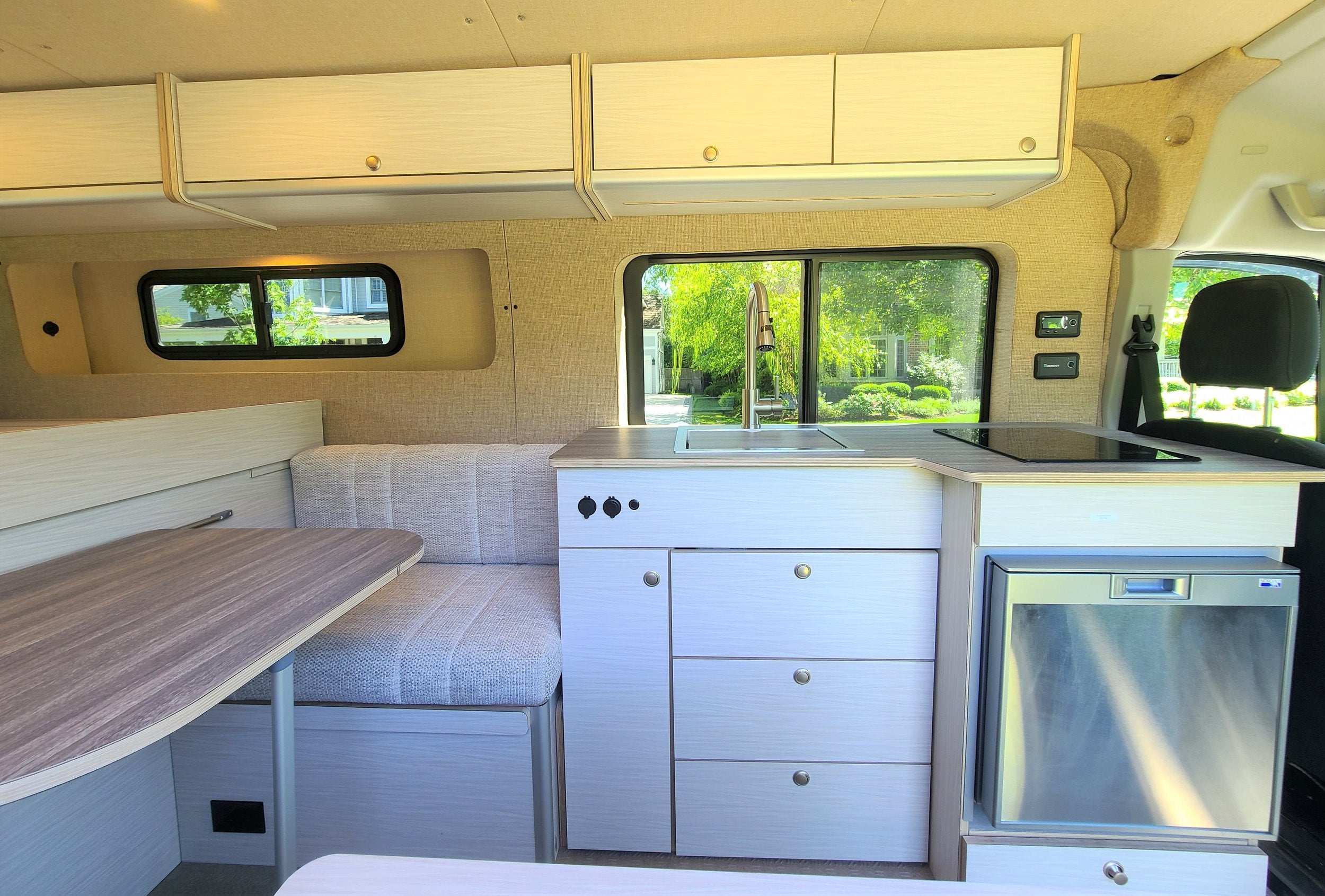 Finished campervan interior with blue cabinetry and wooden countertops reflecting a lightweight yet premium finish.