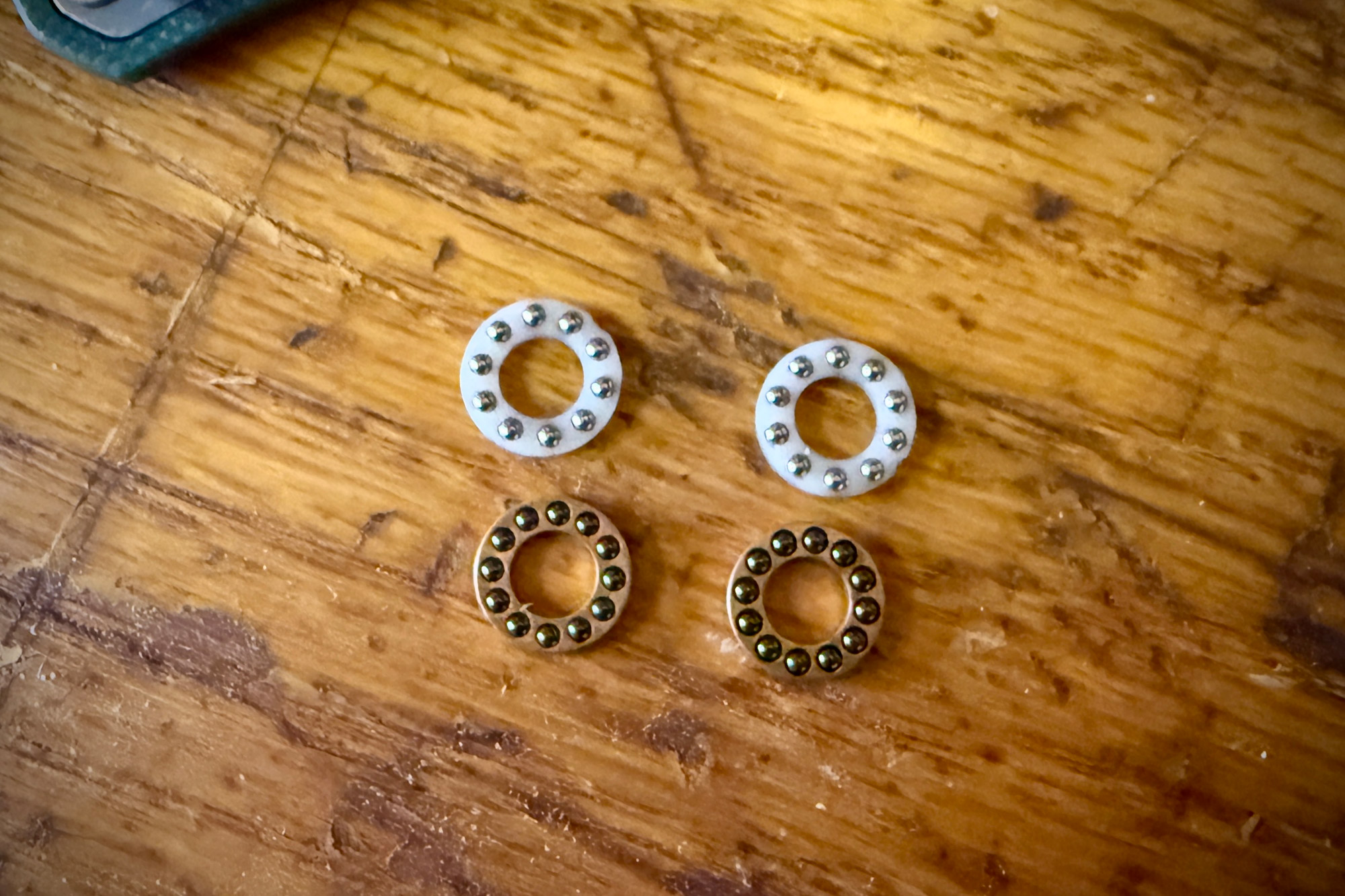 A comparison photo showing the stock pivot bearings positioned above the Skiff Rocket Glide ceramic bearings.