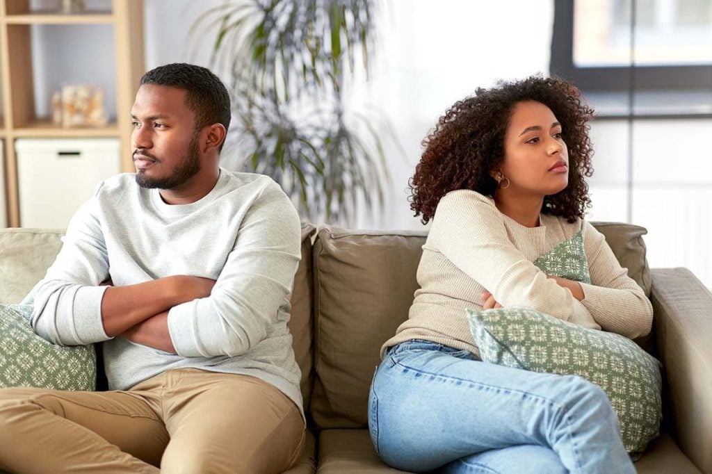 A man and a woman in a indoor setting looking away from each other with tense, distressed expressions.