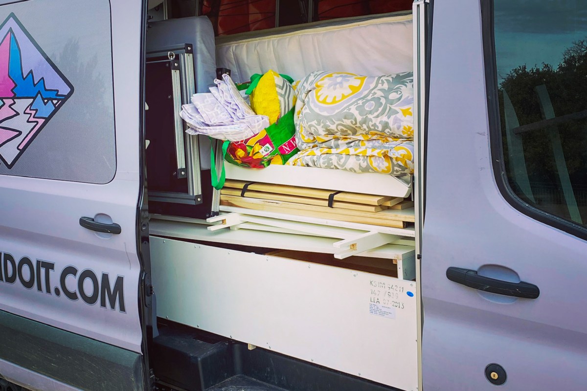 Interior view of a modular campervan with an open floor plan and removable shelving units.