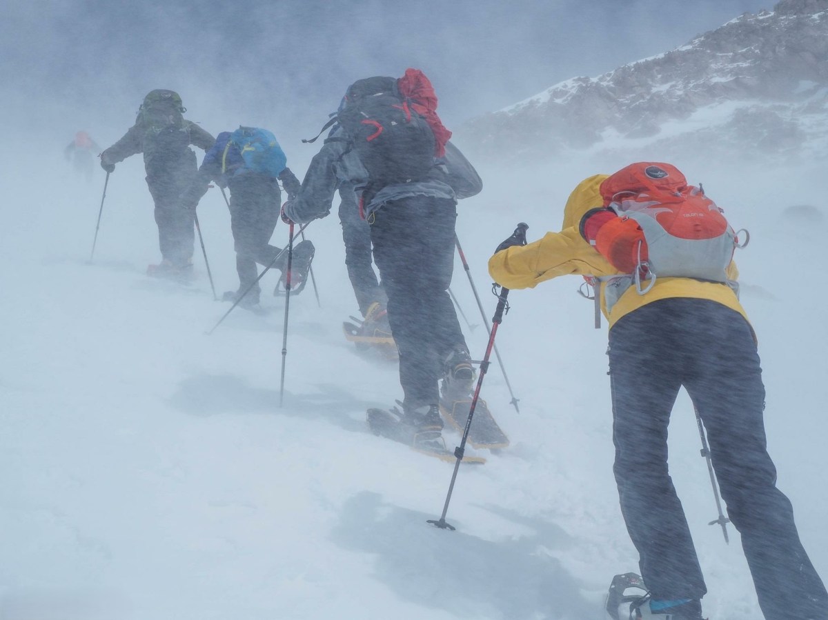 A hiker using technical winter boots with snowshoe bindings in deep powdery snow.
