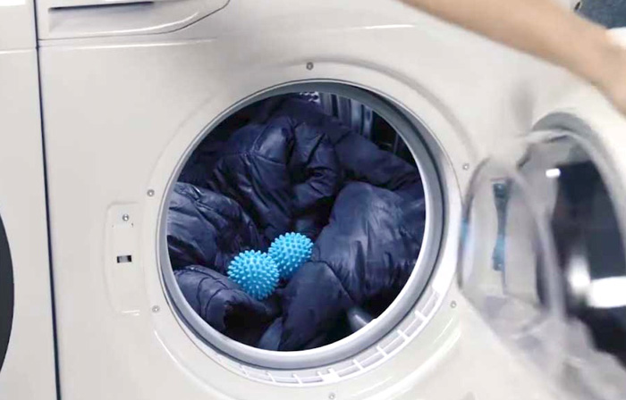 Yellow tennis balls inside a dryer drum with a jacket.