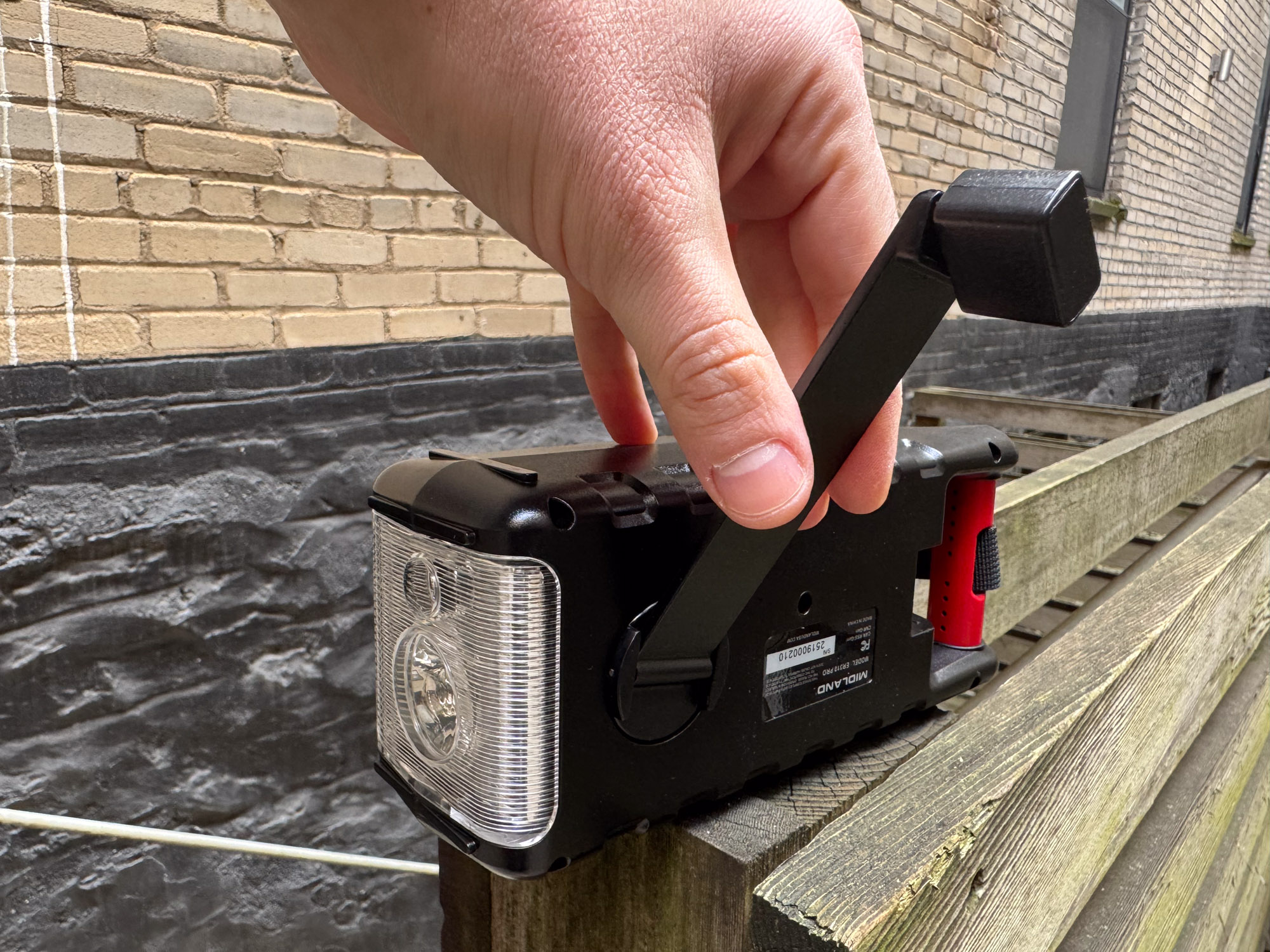A hand operating the manual dynamo crank on the side of the Midland ER310PRO.