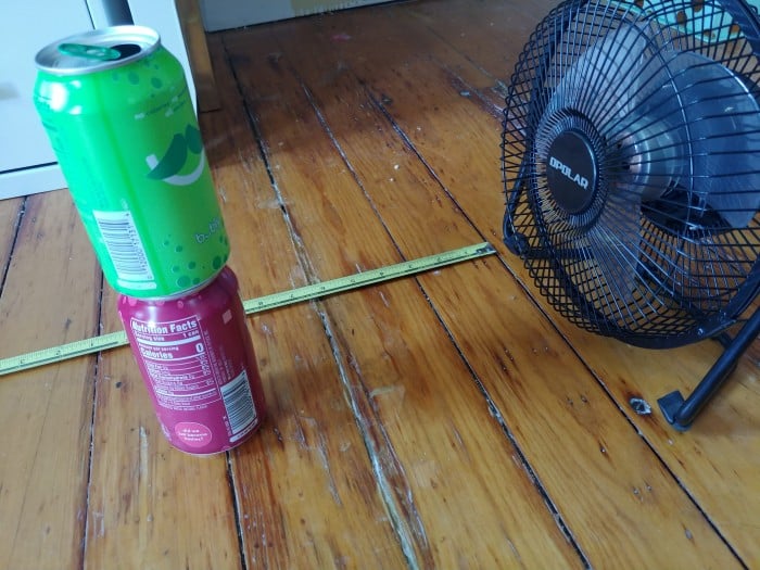 Outdoor fan airflow testing setup using aluminum cans to show wind strength.