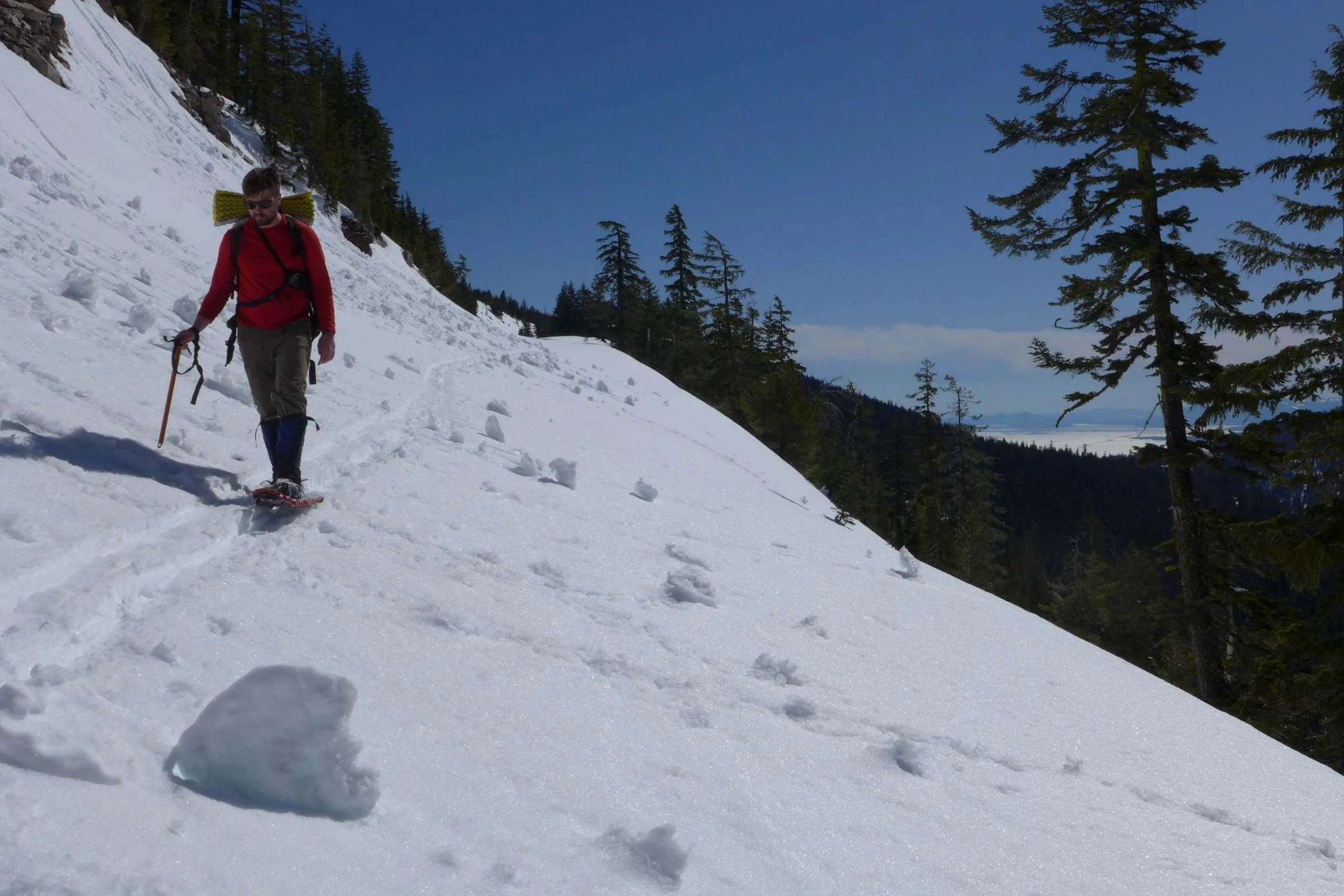 A close-up of a hiker climbing a steep snowy slope wearing MSR Lightning Ascent snowshoes.