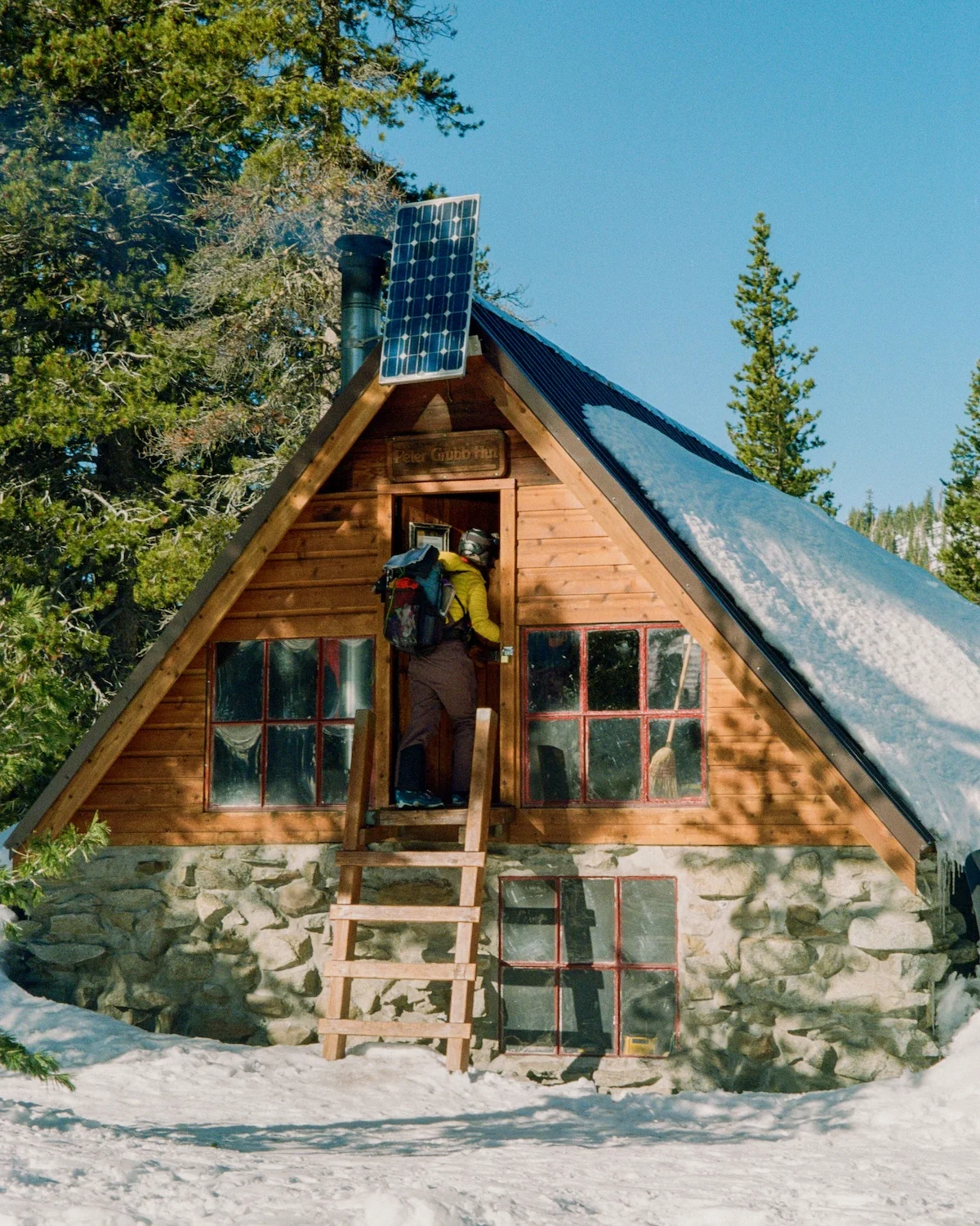 Snow-covered Peter Grubb Hut in a remote mountain meadow.