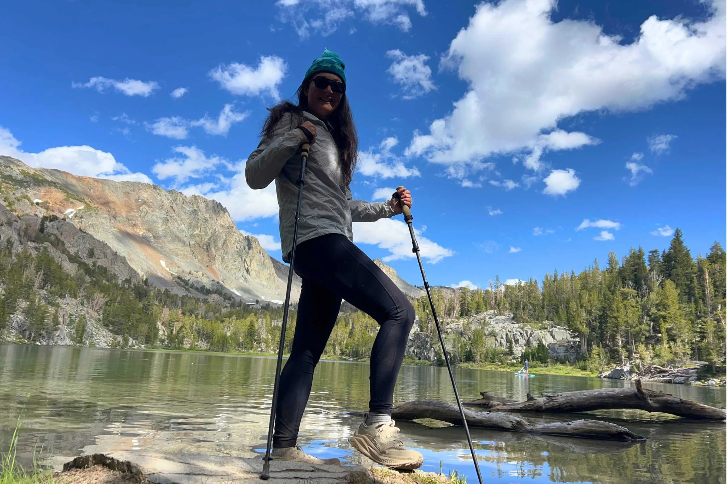 Hiker using trekking poles for balance while crossing a mountain creek
