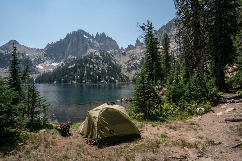 A small tent set up in a mountainous lakeside area, demonstrating the beauty of riparian camping.