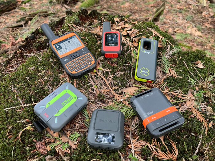 An assortment of modern satellite messenger devices including Garmin inReach and ZOLEO models.