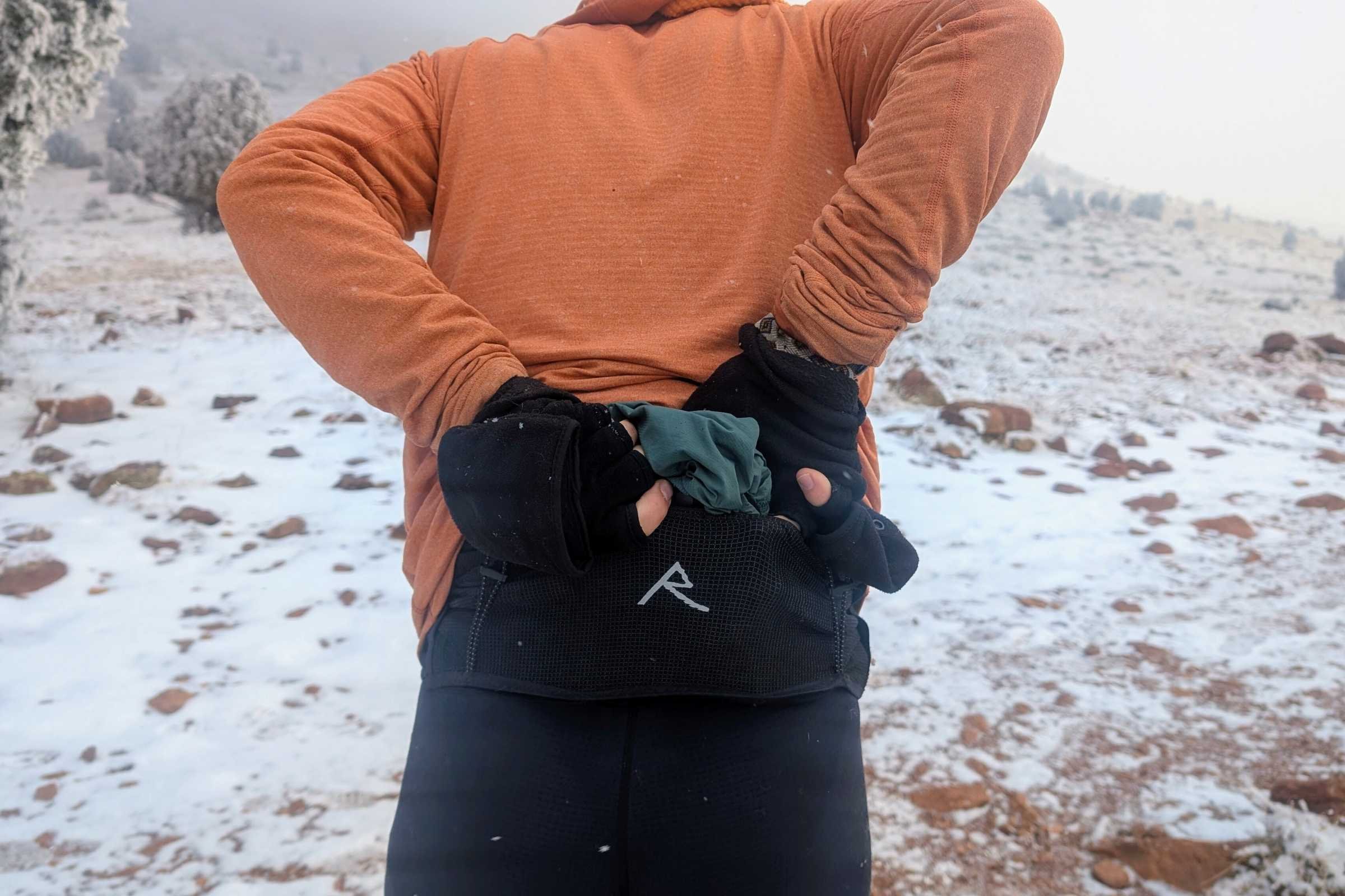 A runner standing on a mountain ridge wearing the Raide Research LF 2L balance belt.