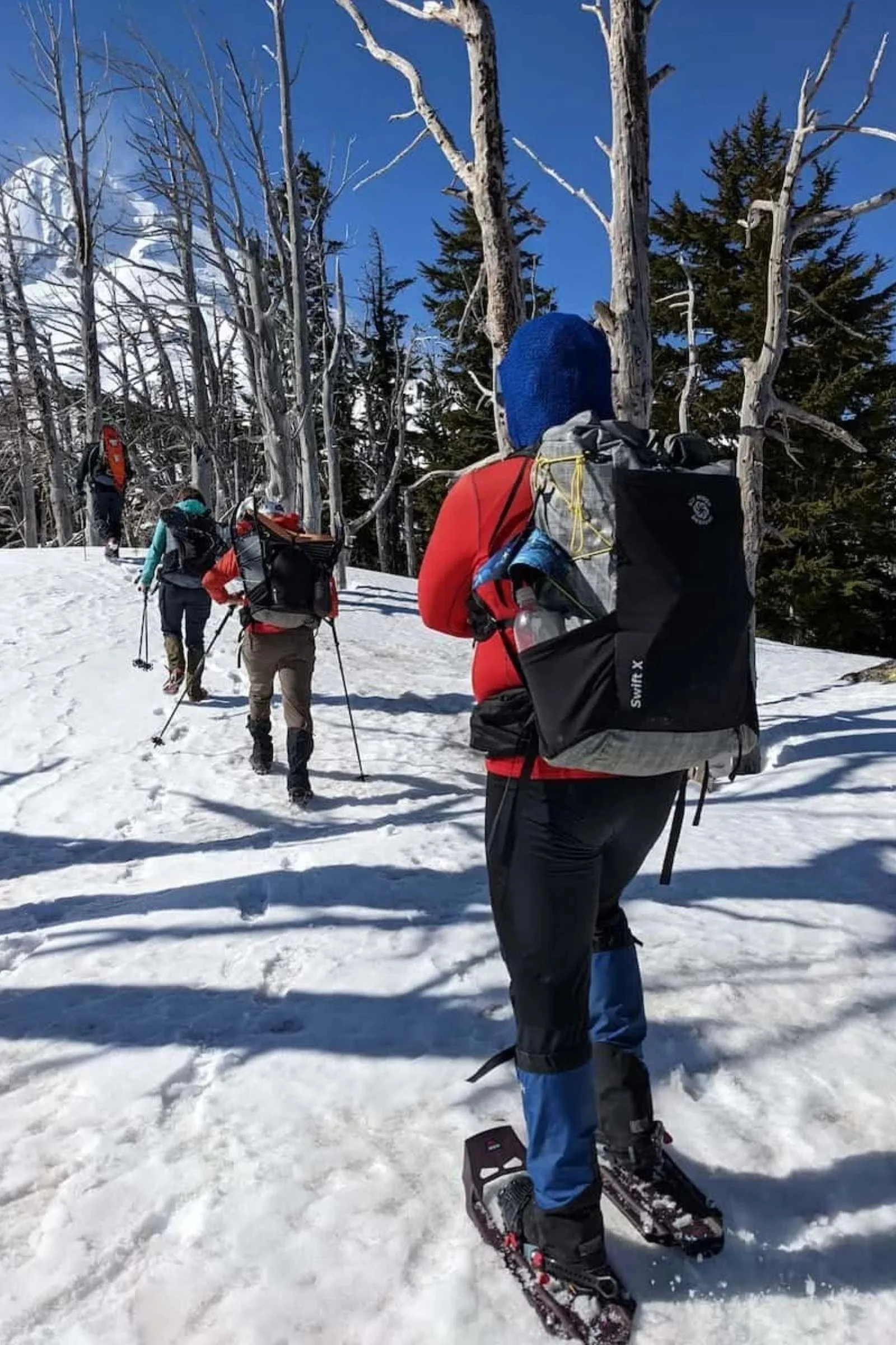 A person wearing MSR Evo Trail snowshoes hiking through hard pack snow.