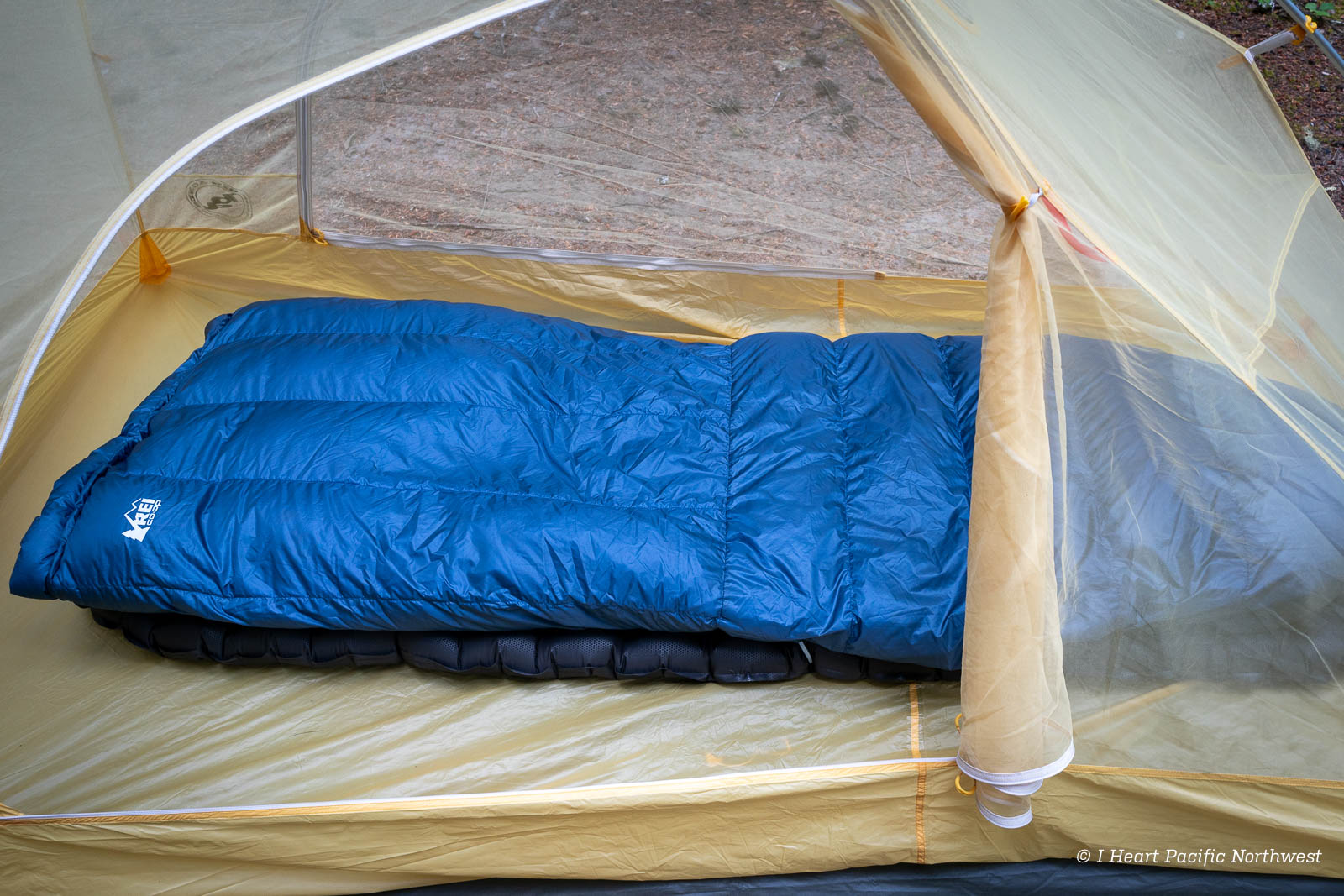A side-by-side illustration comparing a traditional mummy sleeping bag with a lightweight backpacking quilt.