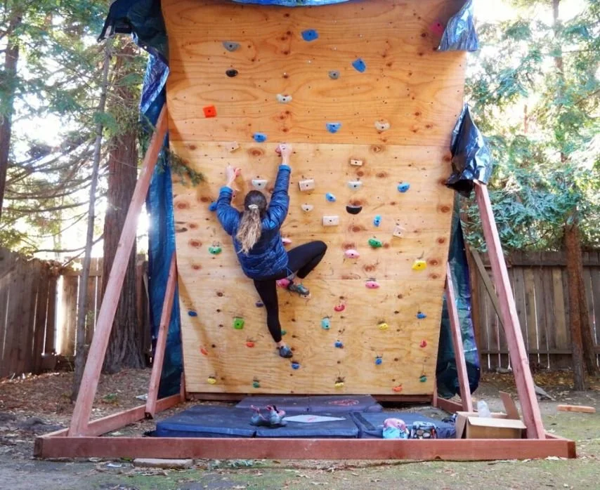 Interior view of a wood-framed climbing wall in a residential setting.