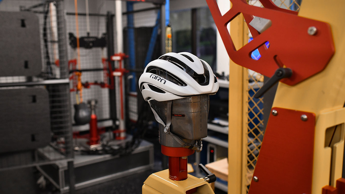 Technical testing rig showing a helmet undergoing impact safety protocols.