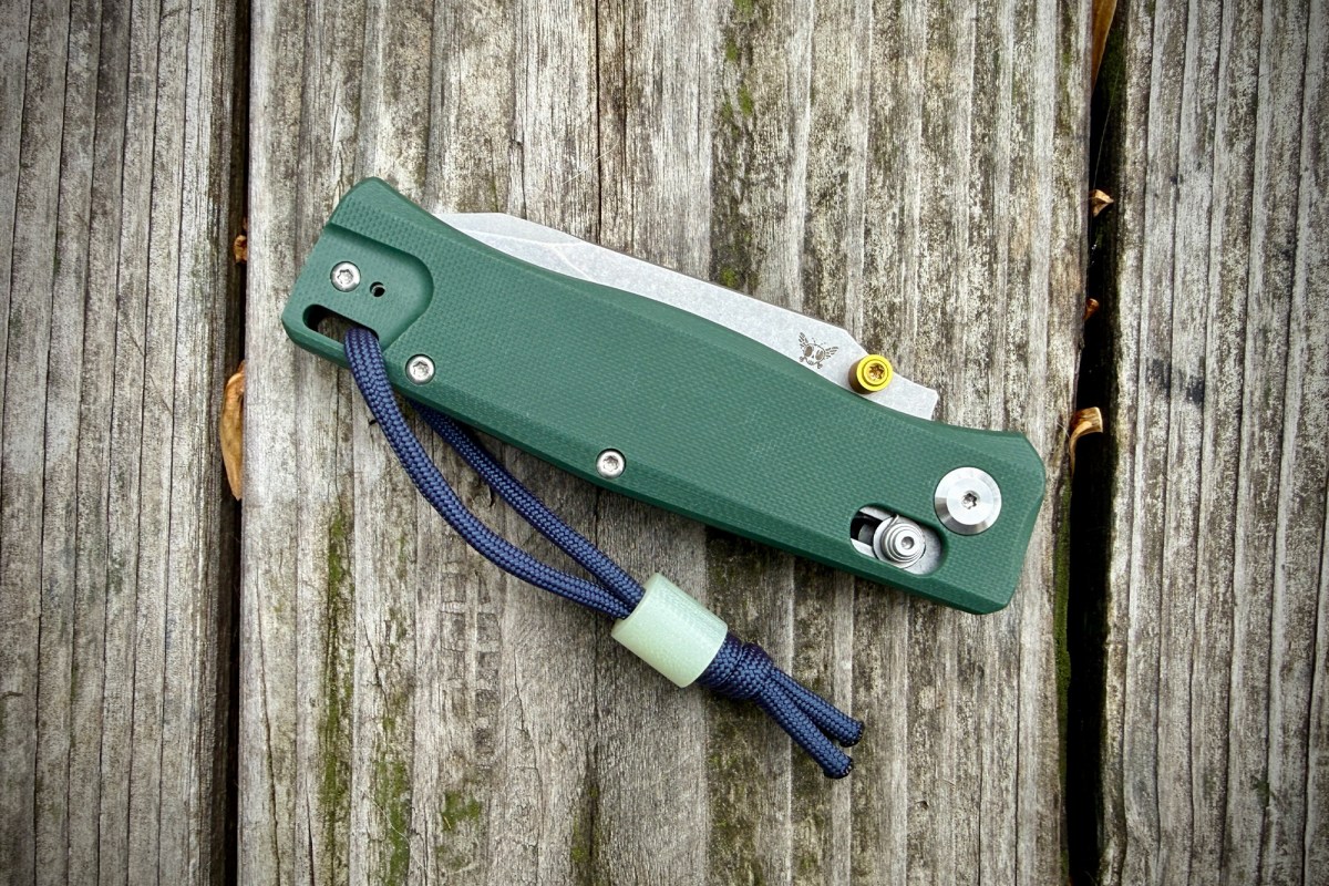 The Flytanium BEEF folding knife in its closed position resting on a weathered wooden surface.