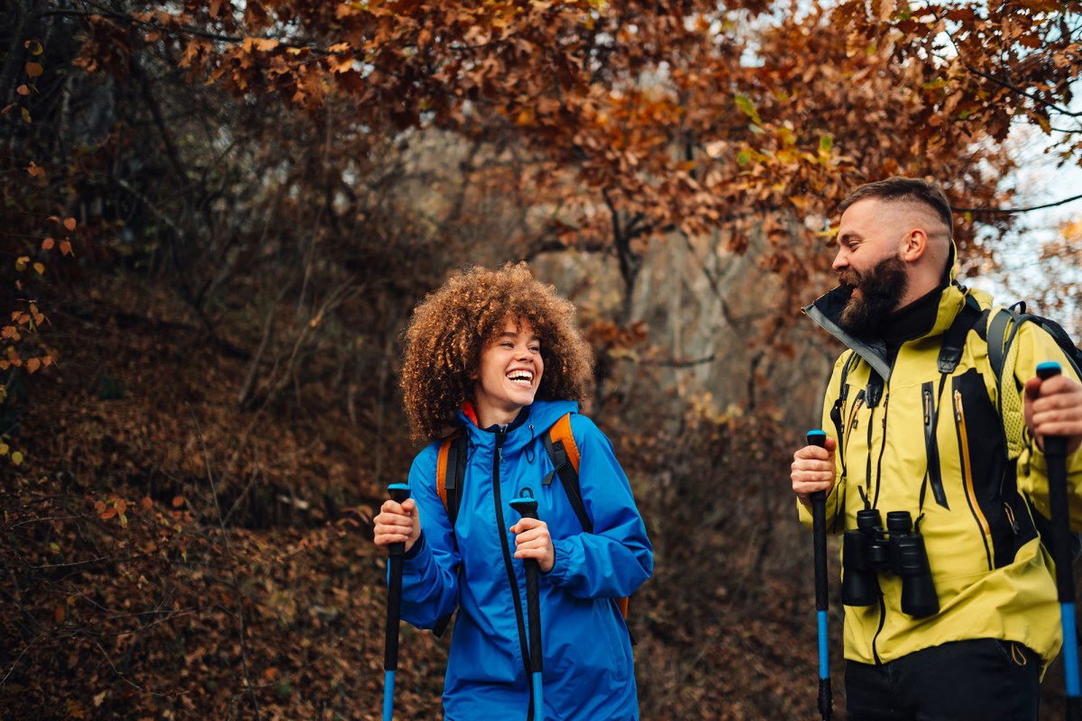 A group of three hikers talking and laughing while walking through a scenic mountain landscape.