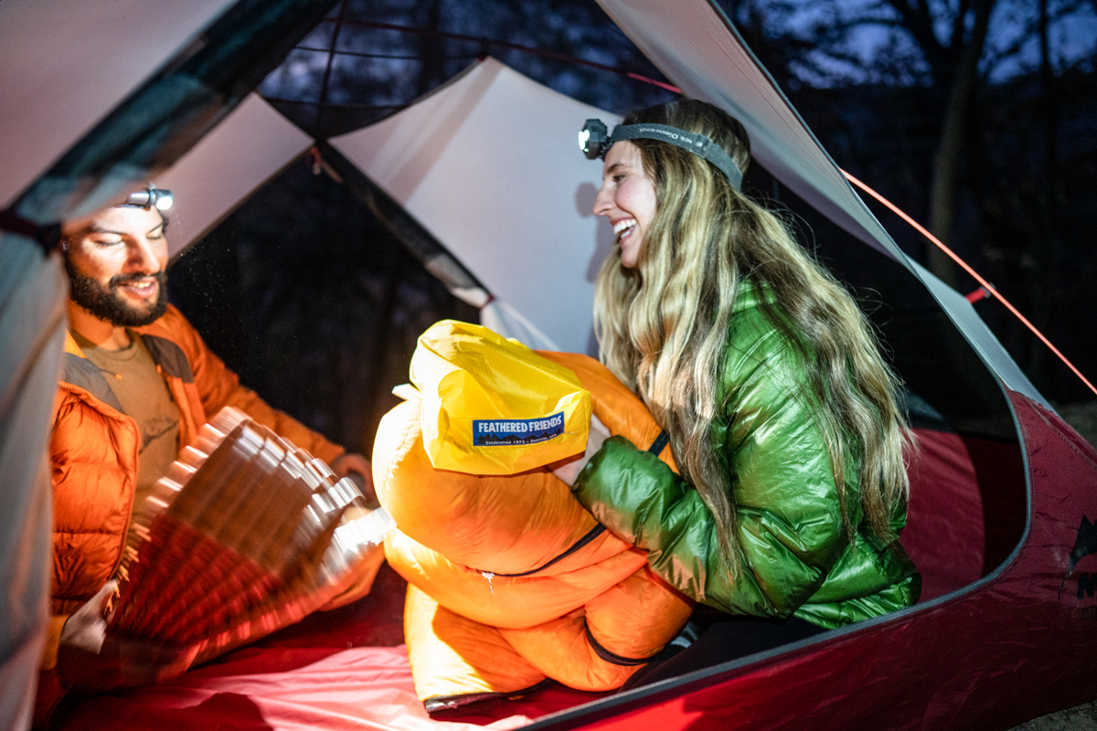A couple unpacking sleeping bags to show the difference in loft and packability.